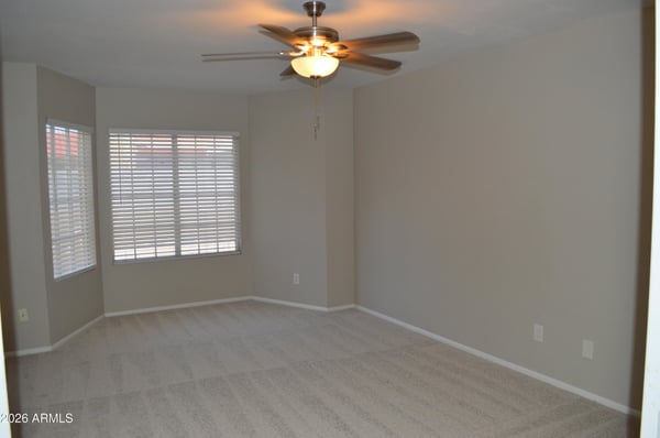 Spacious primary bedroom featuring multiple windows, fresh carpeting, ceiling fan, and a calming neutral color palette. A comfortable retreat designed for relaxation and everyday comfort.