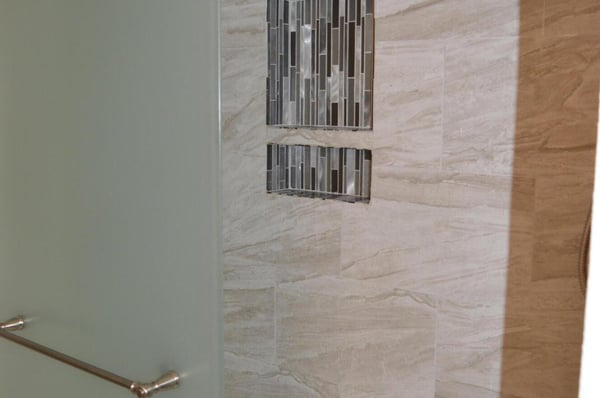 Elegant walk-in shower featuring custom tile, decorative accent niches, and a modern glass enclosure. This beautifully upgraded bathroom showcases craftsmanship and contemporary design.
