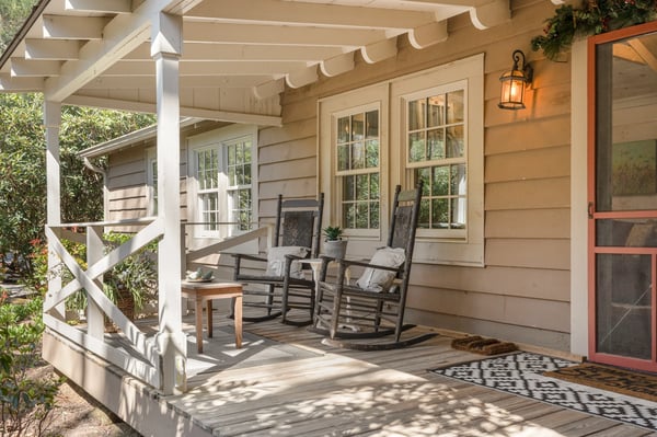Cozy porch with inviting rockers, perfect for enjoying morning coffee amidst lush surroundings.