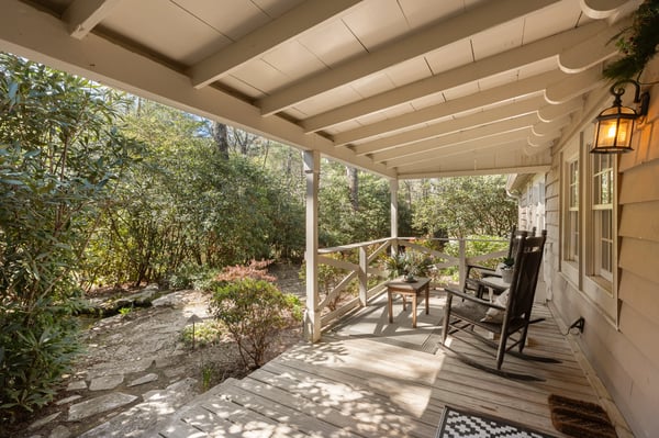 Relax on the inviting porch, surrounded by lush greenery and tranquil landscaping for a peaceful retreat.