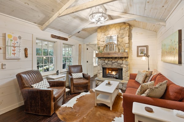Cozy living space featuring a stone fireplace, wood accents, and warm natural light throughout.