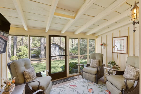 Bright and inviting sunroom with large windows overlooking a private backyard, perfect for relaxation or gatherings.
