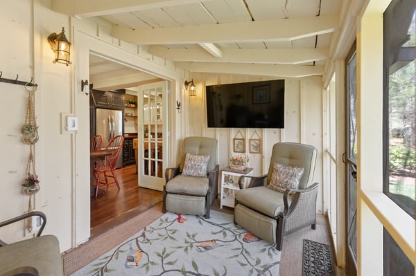 Inviting sunroom features comfortable seating and views, seamlessly connecting to a well-appointed kitchen.