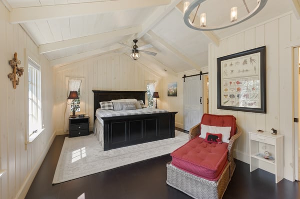 Spacious bedroom featuring vaulted ceilings, natural light, and a cozy reading nook for relaxation.