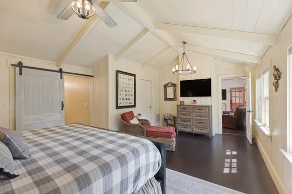Bright, airy bedroom featuring vaulted ceilings, large windows, and a cozy sitting area for relaxation.