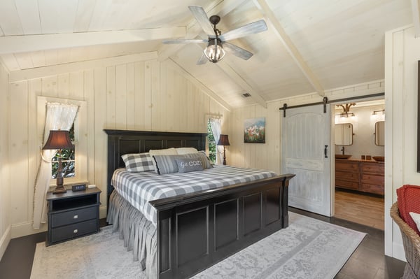 Cozy bedroom featuring a vaulted ceiling, modern fixtures, and seamless access to an adjoining bathroom.