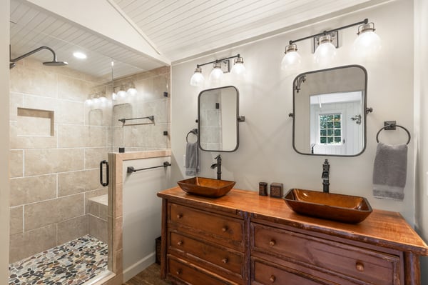 This modern bathroom features dual vessel sinks, a spacious walk-in shower, and tasteful decor throughout.