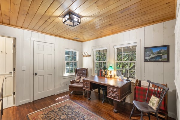 Bright, inviting office space featuring wood paneling, large windows, and a cozy workspace for productivity.