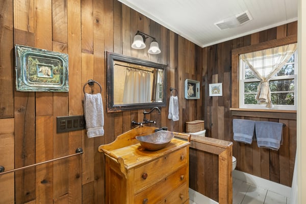 This unique bathroom features rustic wood panels and a distinctive bowl sink for a cozy ambiance.