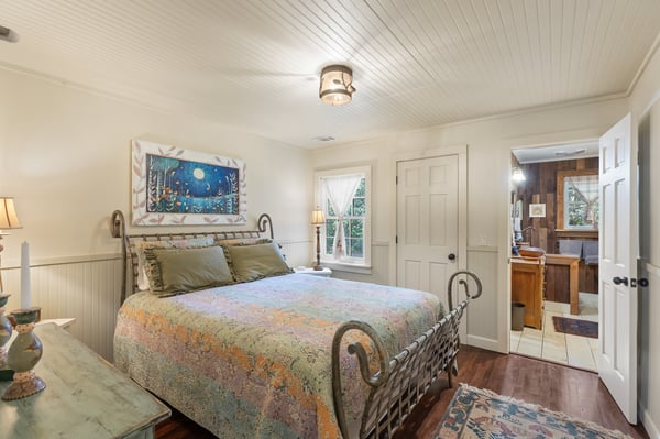 Cozy bedroom featuring a vintage bed frame, natural light, and direct access to a modern bathroom.