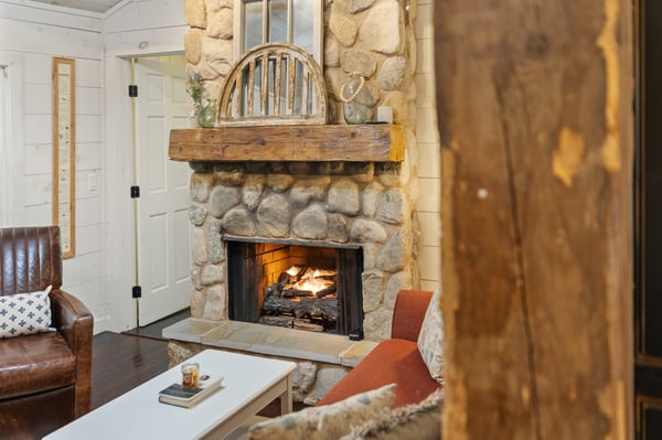 Cozy living area featuring a rustic stone fireplace and warm wood accents, perfect for comfortable gatherings.