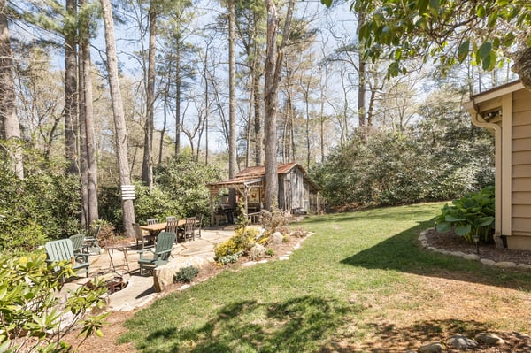 Tranquil outdoor space featuring a cozy shed, patio seating, and lush greenery, perfect for relaxation.