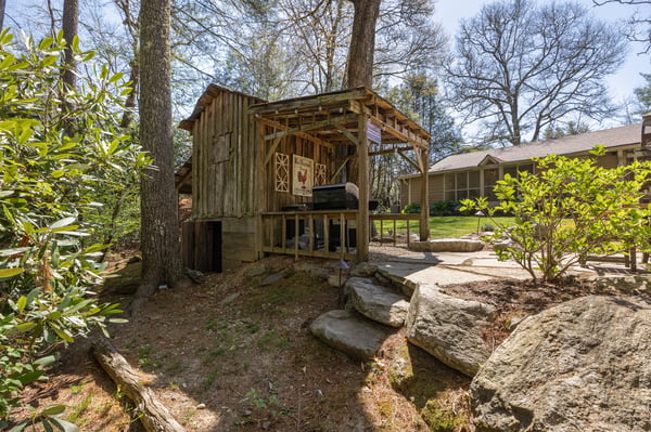 Rustic outdoor gathering space among mature trees, perfect for relaxing and entertaining in nature.