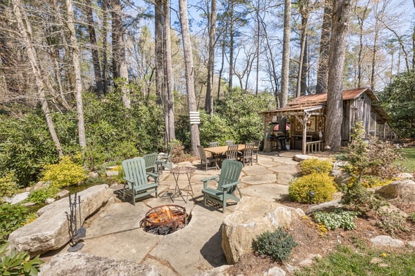 Discover a unique outdoor retreat featuring a cozy fire pit, natural stone seating, and a rustic shed.