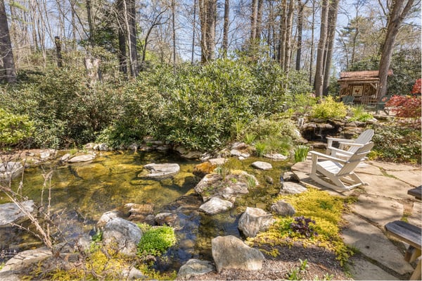 Discover a private retreat featuring a tranquil pond surrounded by lush greenery and natural stone pathways.