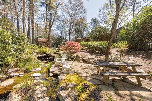 Discover a tranquil outdoor space featuring a pond, diverse landscaping, and ideal seating for relaxation.