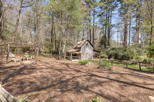 Quaint property features a rustic cabin surrounded by lush greenery and ample outdoor space for relaxation.