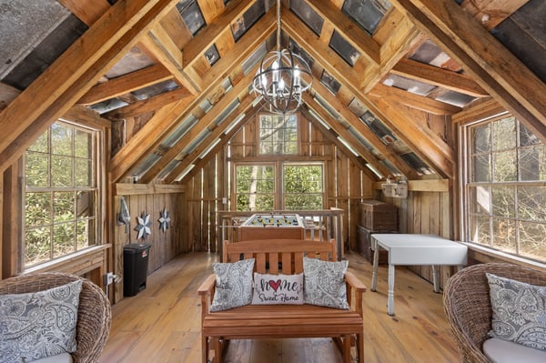 Cozy retreat featuring rustic wood beams, ample natural light, and inviting spaces for relaxation and creativity.