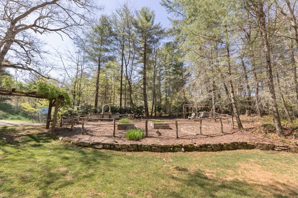 Spacious outdoor area surrounded by trees, ideal for gardening or recreational activities, in a peaceful setting.