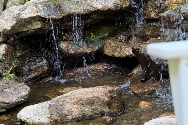 Tranquil water feature surrounded by natural stone, enhancing the outdoor ambiance of this property.