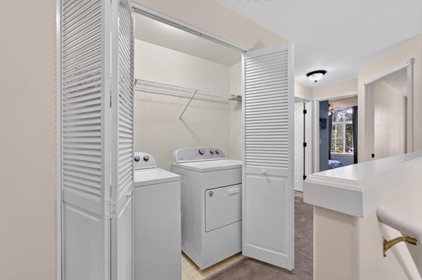 Bright and efficient laundry area featuring convenient side-by-side washer and dryer with ample storage space.