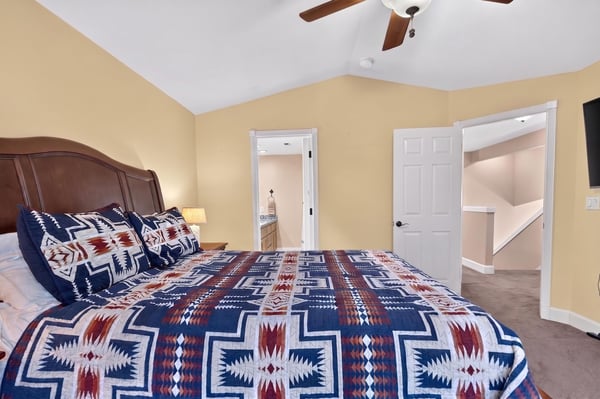 Spacious bedroom featuring a unique patterned bedspread, high ceilings, and convenient access to a multi-level layout.