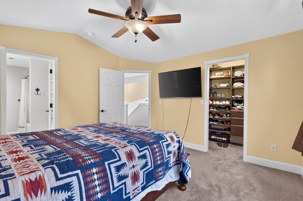 Cozy bedroom featuring a ceiling fan, spacious closet, and direct access to modern amenities.