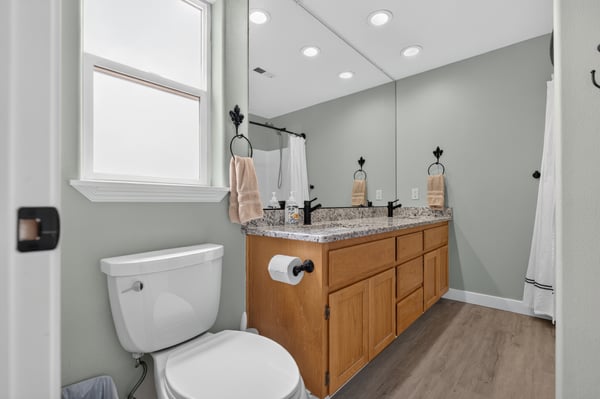 Modern bathroom featuring dual sinks, granite countertops, and ample natural light, perfect for daily routines.