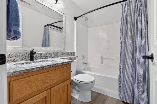 Modern bathroom featuring granite countertops, a spacious tub, and a sleek, organized design for functionality.