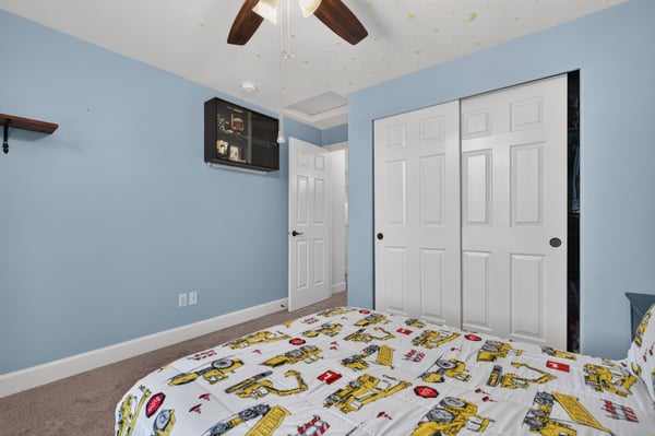 Bright bedroom featuring cozy carpeting, ample storage with double closets, and fun patterned bedding.