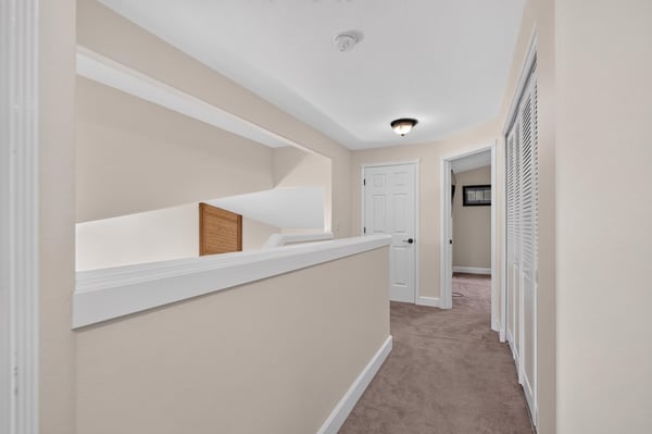 Bright and spacious hallway leading to multiple rooms, featuring soft carpet and modern design elements.