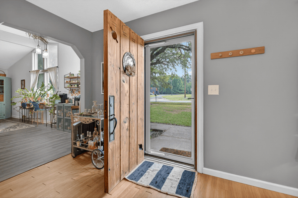 Welcoming entryway featuring a solid wooden door, leading to an inviting, open living space with abundant natural light.