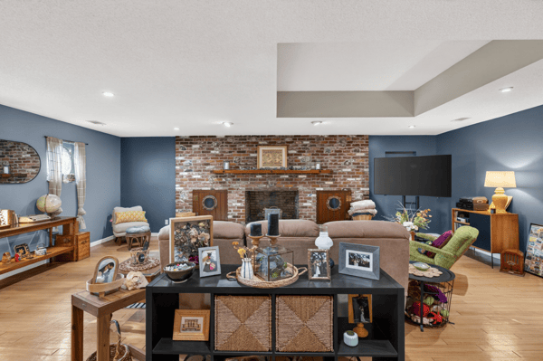 Spacious living area featuring exposed brick accents, ample natural light, and versatile entertainment options.
