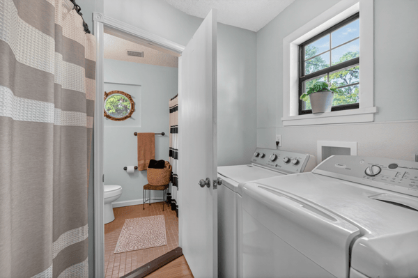 Bright and functional laundry area seamlessly connecting to a full bathroom.