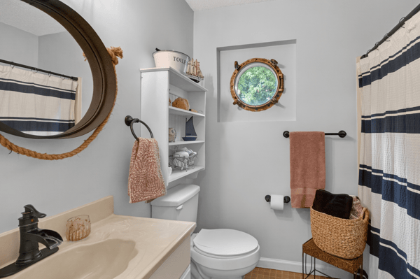 Bright bathroom featuring modern fixtures, a unique round window, and ample storage for convenience.