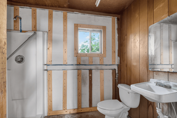 This unfinished bathroom features a shower area, sink, and window for natural light, ready for renovation.
