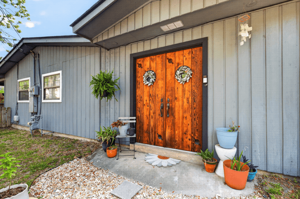 Inviting rear entryway featuring distinctive double doors and vibrant planters, perfect for welcoming guests home.