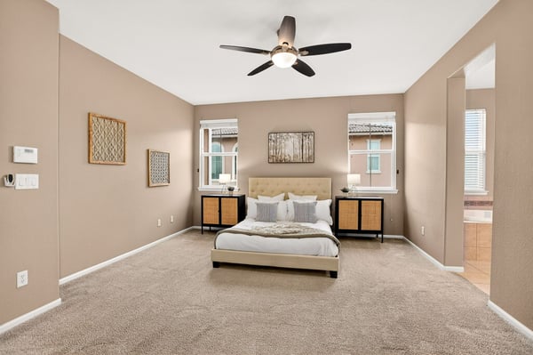 Spacious bedroom featuring abundant natural light, modern ceiling fan, and plush carpeting for comfort.