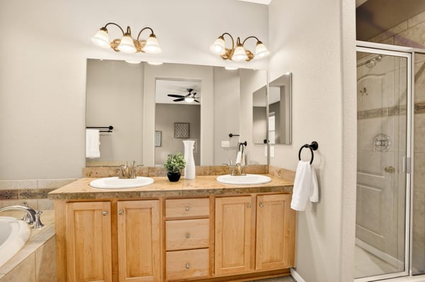 Modern bathroom featuring dual sinks, spacious counter, and a glass-enclosed shower for convenient living.