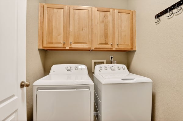 Bright laundry room featuring ample storage and modern appliances, designed for efficiency and convenience.