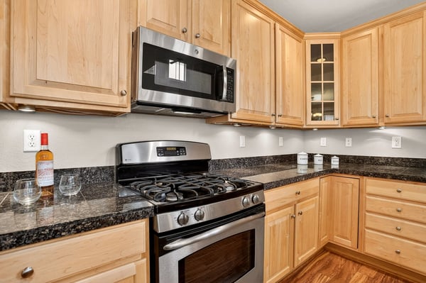 Modern kitchen featuring granite countertops, stainless steel appliances, and ample cabinet space for storage.