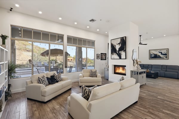 Light-filled living room with large windows, fireplace, and patio views showcases Scottsdale indoor-outdoor lifestyle and modern design.