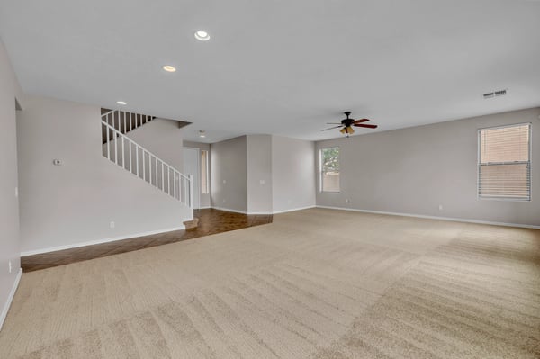 Open living room with fresh carpet, neutral finishes, and plenty of natural light, perfect for relaxing or hosting guests.