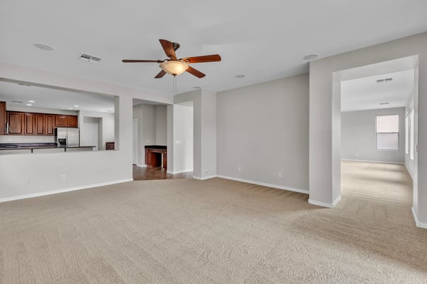 Wide-open living area with soft carpet and direct sightlines into the kitchen, highlighting the home's functional layout and updated finishes.