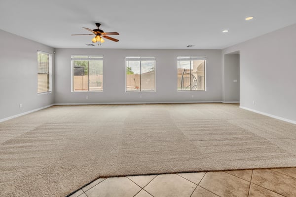 Large family room featuring multiple windows, neutral tones, and comfortable carpet, ideal for relaxing or entertaining guests.