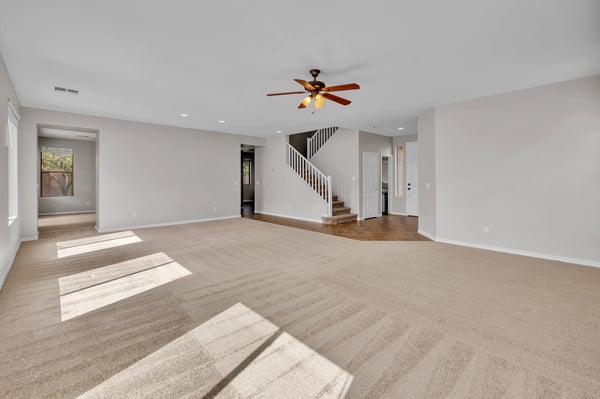 Sunlit living space with expansive carpeted area and open layout, perfect for modern living in this Goodyear property.