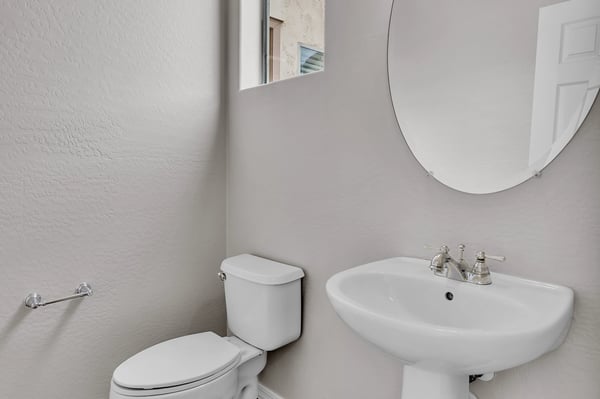 Clean and functional half bath with pedestal sink and neutral finishes, conveniently located for guests.