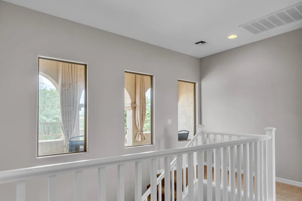 Open upstairs hallway with natural light and railing detail, connecting bedrooms while enhancing the home's spacious feel.