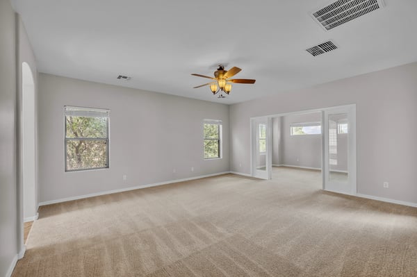 Bright and airy primary bedroom with multiple windows and soft carpeting, creating a relaxing retreat in this Goodyear home.
