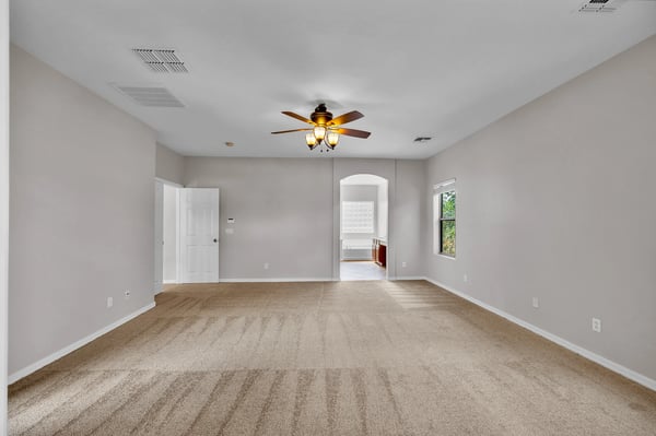 Inviting bedroom space featuring plush carpet, ceiling fan, and natural light for everyday comfort.